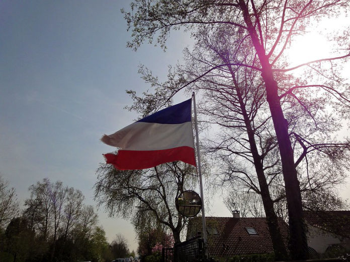 Een beschadigde en gescheurde Nederlandse vlag, ondersteboven gehesen in een vlaggenmast.
